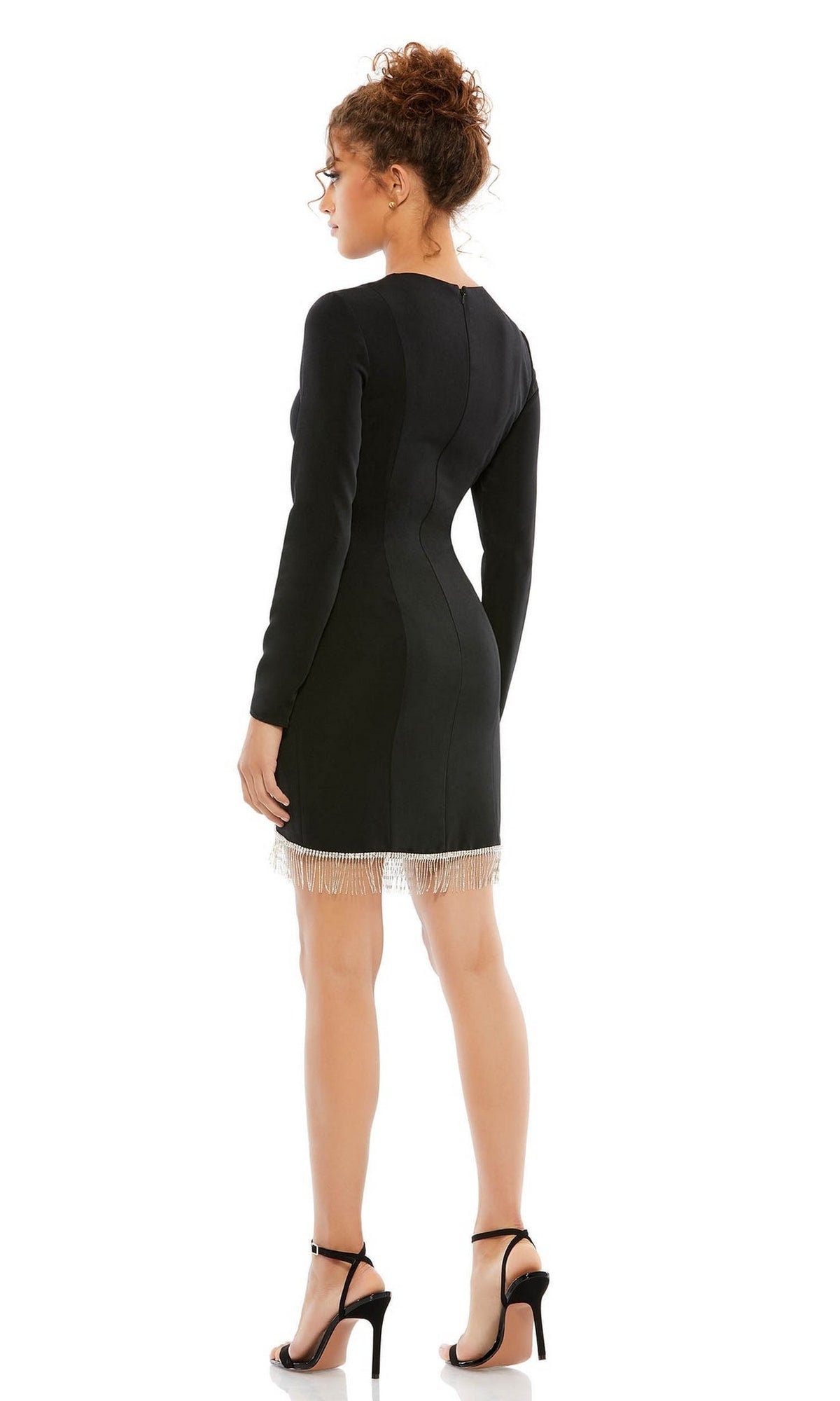 A woman faces away, wearing the Short Homecoming Dress 26679 by Mac Duggal—a black, long-sleeve fitted dress with a beaded fringe hem—paired with black high-heeled sandals.